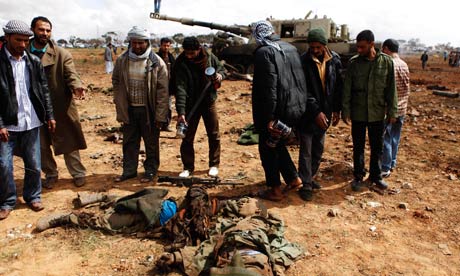 People look at the bodies of loyalist soldiers on the outskirts of Benghazi