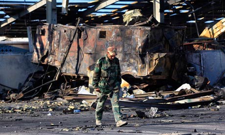 A Libyan soldier walks pass a naval military facility damaged by air strikes in Tripoli