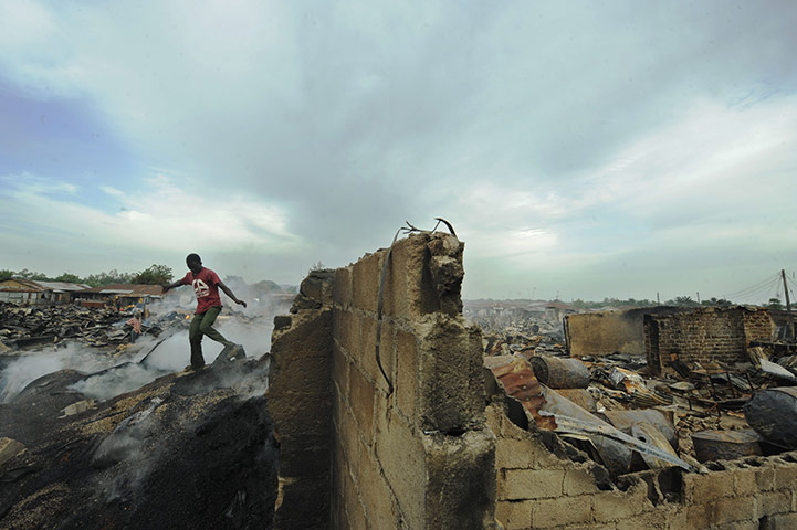 Africa Unrest: A young man walks among still smouldering grain in Kaduna, Nigeria