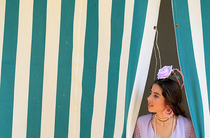 Feria de Seville: A woman wearing traditional clothes looks out from a stall