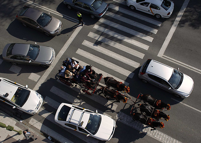 Feria de Seville: A carriage moves forward among cars next to the Maestranza bullring
