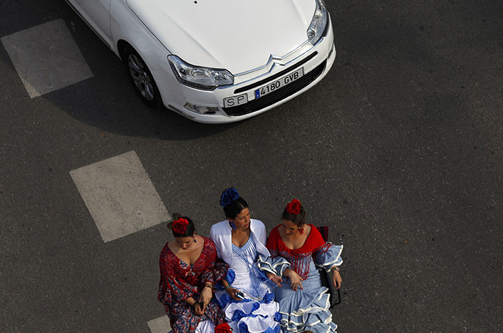 Feria de Seville: Women wearing traditional Sevillana dresses sit on a carriage