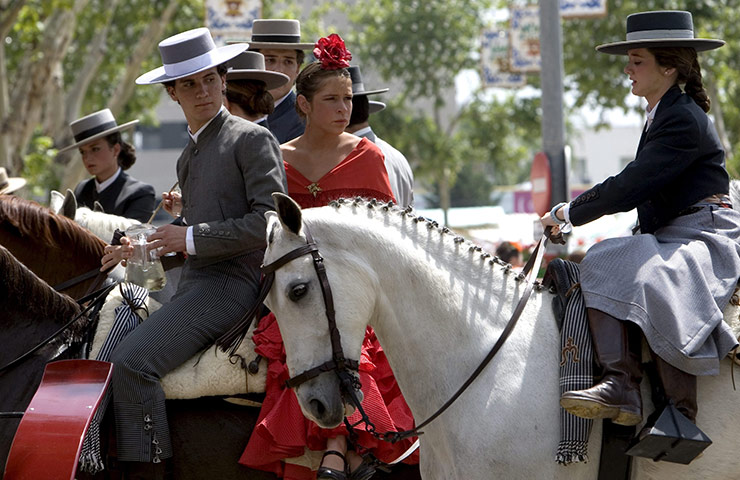 Feria de Seville: People wearing traditional dresses ride horses
