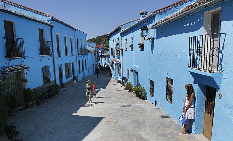 Juzcar: Blue Town: People walk trough the streets of the village of Juzcar