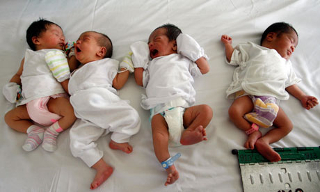 Babies lie on a bed in maternity ward in Manila