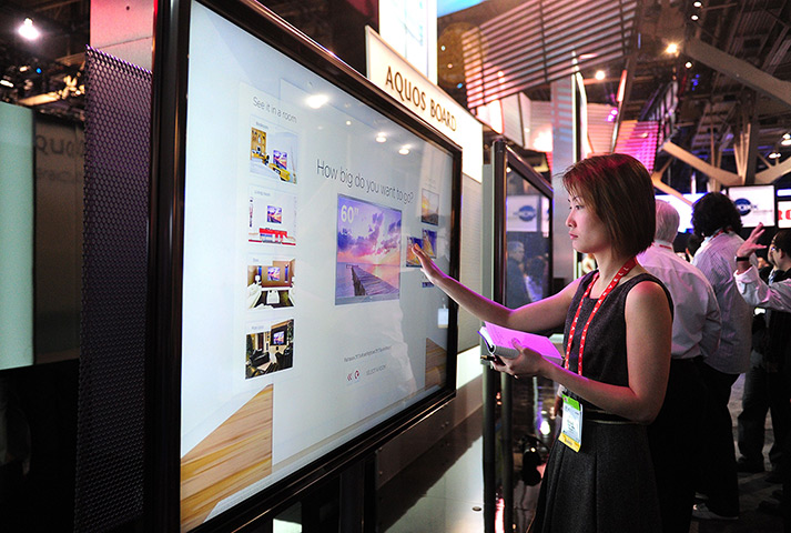 CES 2012: A woman touches the screen on Sharp's 80-inch touch screen TV Aquos Board
