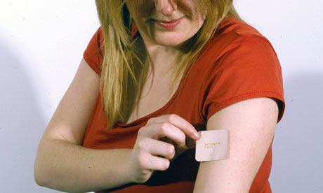 A woman applying a nicotine patch to her arm