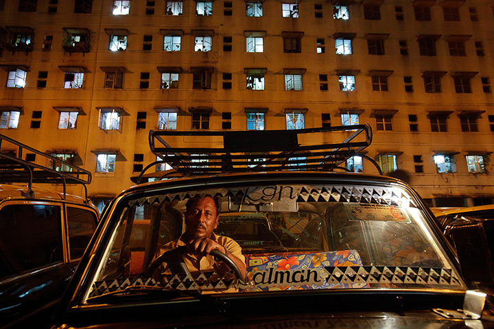 Mumbai taxis: A driver waits for customers in front of an apartment in Mumbai's suburbs