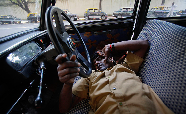Mumbai taxis: A taxi driver takes an afternoon nap with his hand on the steering wheel 