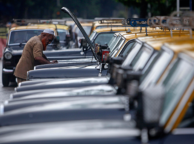 Mumbai taxis: A taxi driver inspects the engine of his taxi at a taxi rank