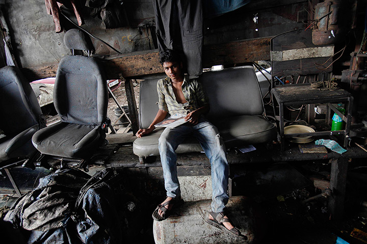 Mumbai taxis: A mechanic sits on a seat salvaged from a scrapped taxi at a workshop