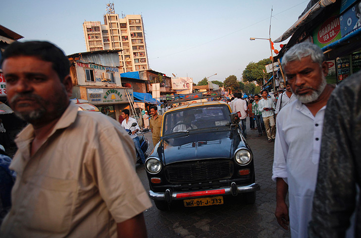 Mumbai taxis: A taxi makes it way through pedestrians and traffic on a crowded street 