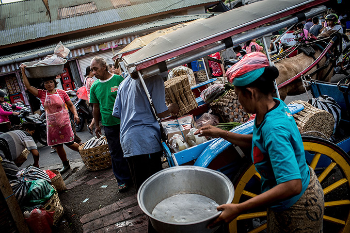 Vanishing Dokar, Bali: Kusir, Nyoman Mantra Manik, helps as passengers load up his Dokar