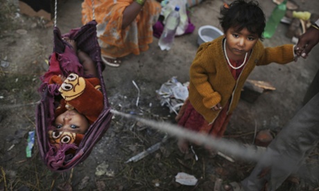 Indian baby Priya hangs in a makeshift bed as her sister stands next to her at a shanty where their family lives New Delhi, India.