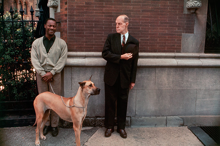 Joel Meyerowitz Monograph: A suited white and casual black man stand with dog