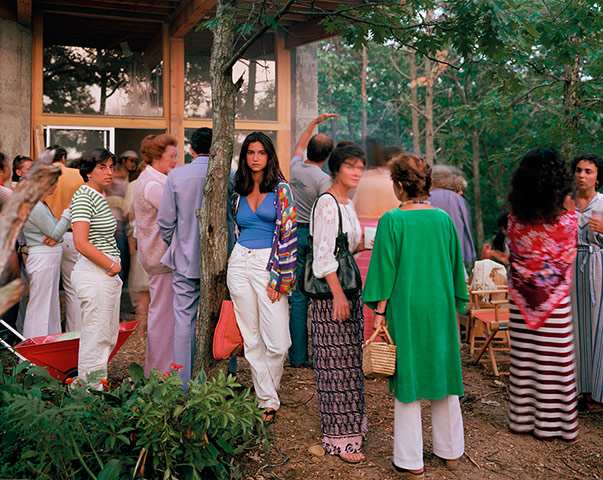 Joel Meyerowitz Monograph: A woman stands looking at camera amonst tourists in Wellfleet