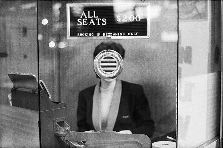 Joel Meyerowitz Monograph: A woman's face is obscured by speaker in ticket booth