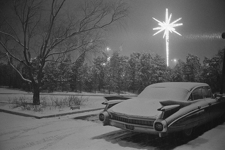 Joel Meyerowitz Monograph: A car is parked in snowy night with Christmas star behind