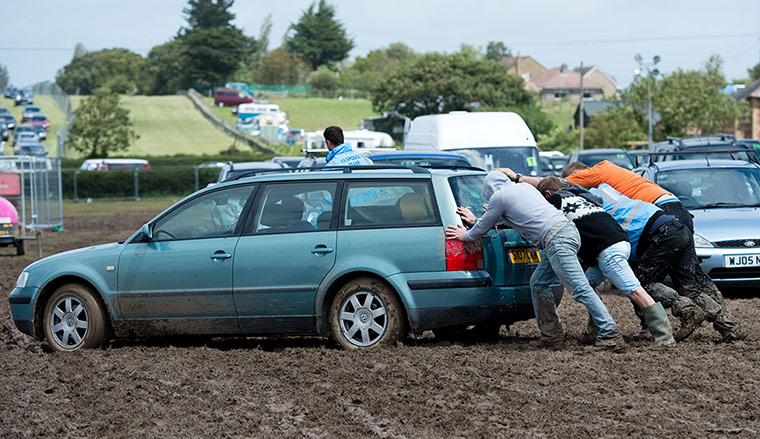 ISle of Woght: Festival-goers attempt to push a car out of the mud