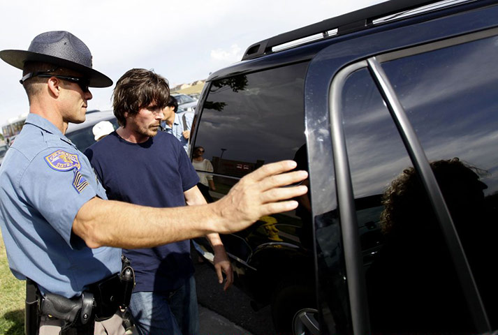 baleaurora: Christian Bale is guarded by a state trooper as he leaves Aurora memorial