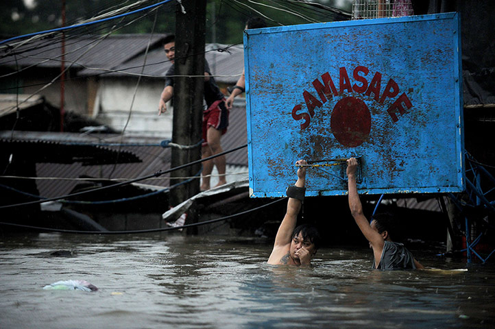 Floods in Manila: Two men hang onto a basketball hoop 