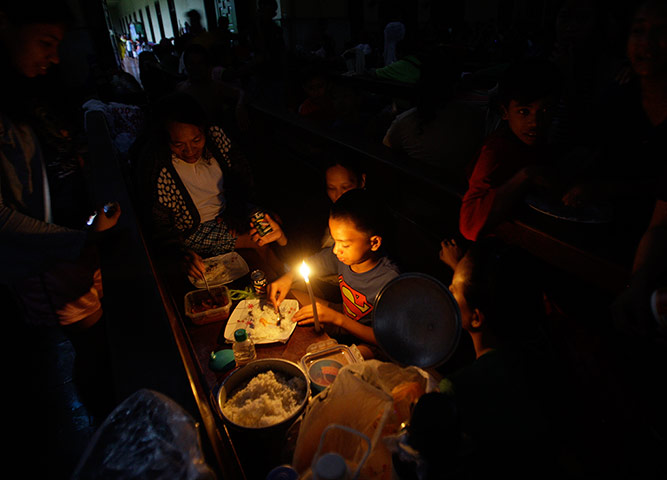 Floods in Manila: An evacuee takes his dinner under candelight 