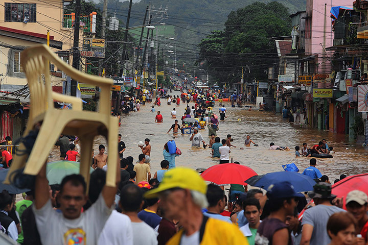 Floods in Manila: Filipinos walk in floodwaters on a main road of Marikina City