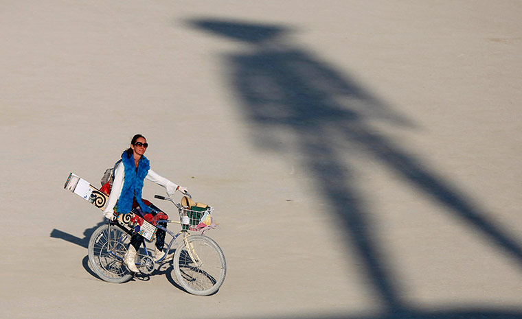 Burning Man: A participant rides past the shadow of the Man during the Burning Man 2012