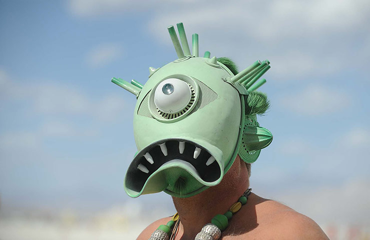 Burning Man: A man with a creature mask walks the playa at Burning Man 2012