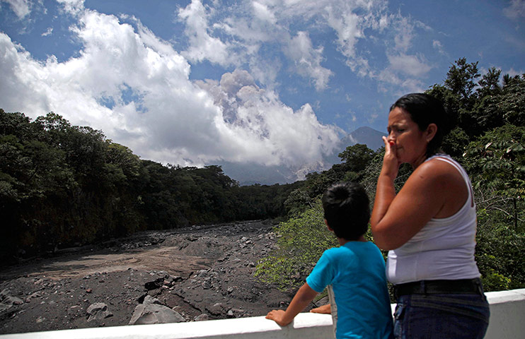 Volcan del Fuego: A boy watches smoke and volcanic ash rise from Fuego Volcano