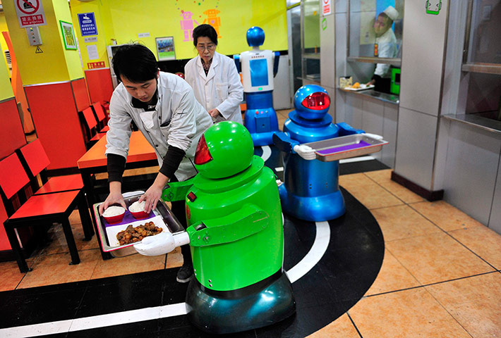 Robot Restaurant: Human waiters assist the robots in loading the trays of food