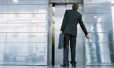 Businessman in front of elevator holding briefcase