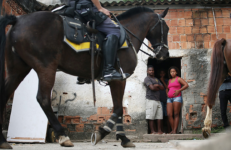 Favela clearance: Residents watch police as they patrol on horseback patrol during a pacifica