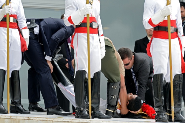 An honour guard soldier receives first aid after he fainted in the intense heat, before the arrival of French President Francois Hollande at Planalto Palace in Brasilia.