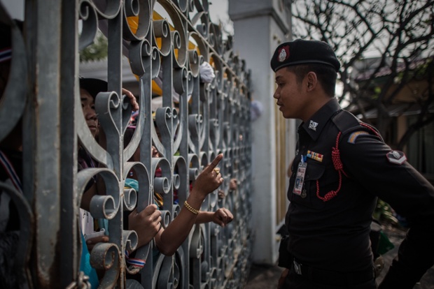 An anti-government demonstrator points his finger at a policeman as they talk through the gate of the Government House in Bangkok, Thailand.