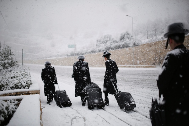 Ultra-Orthodox Jewish men walkin the snow in Jerusalem. Public transport was briefly suspended after heavy snowfall.