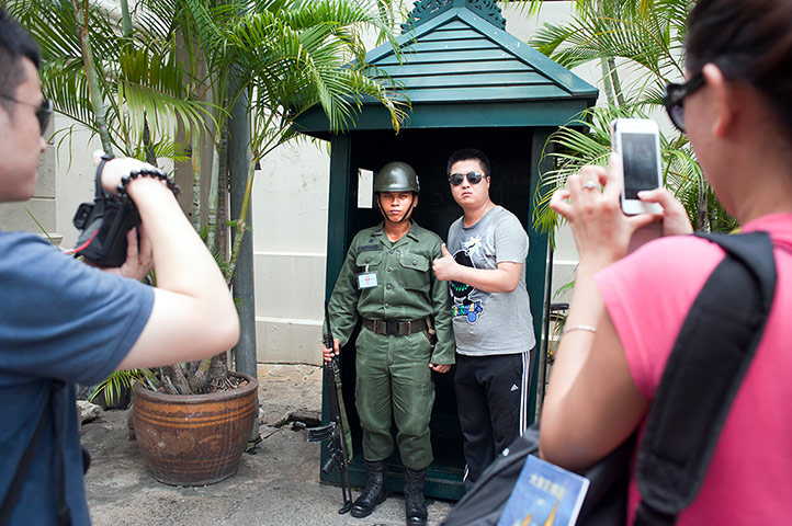 Chinese tourists: Tourists take turns posing with a guard by the exit to the Grand Palace