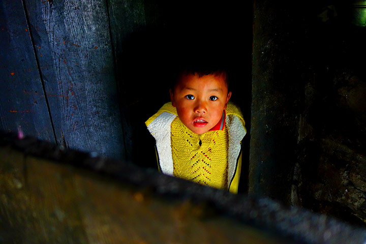 Readers' photos: colour: Bsmall village near the Buddhist monastery town of Tawang in the Himalayas, I spotted this shy little boy all in yellow watching me from behind a door. I managed to coax him out and was invited into his house by his grandmother and sat drinking traditional yak butter tea while she worked on her loom and he hid in her skirts. The whole village is made from tarred black wood and it was a cold and grey day, so his outfit really stood out. This area of India is ethnically Tibetan and is largely off limits to outsiders. It's a truly amazing place with such kind people, and is unbelievably photogenicoy near Tawang in the Himalayas