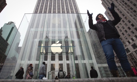 A man poses for a photo in front of the Apple store on 5th Avenue in New York.
