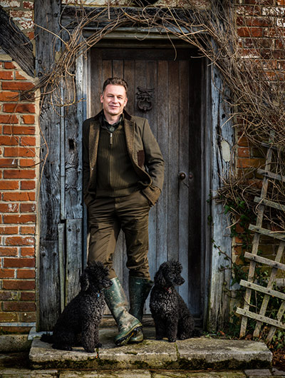 ChrisPackhamHampshire: The presenter Chris Packham standing outside a door, with two black dogs