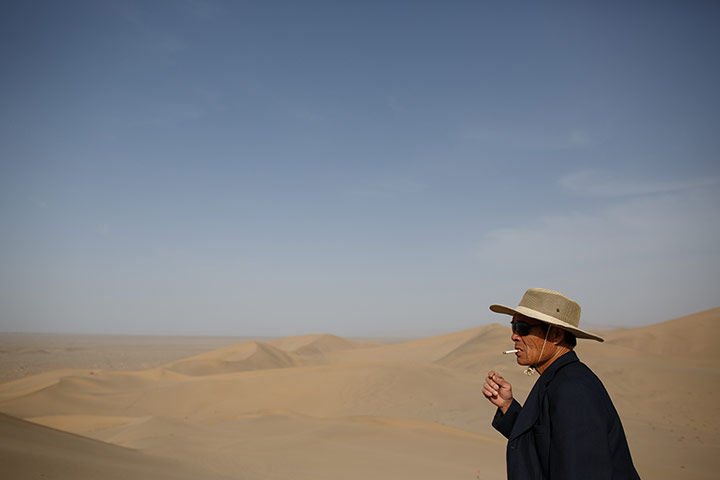 Crescent lake in China: Man smoking in dunes around Crescent lake