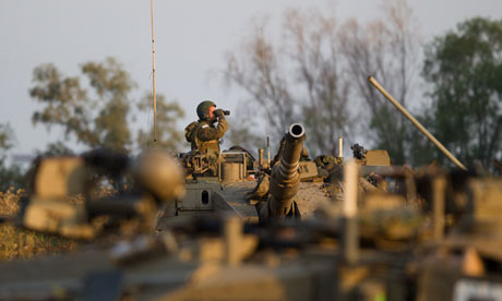 An Israeli soldier looks through his binoculars from the top of his tank