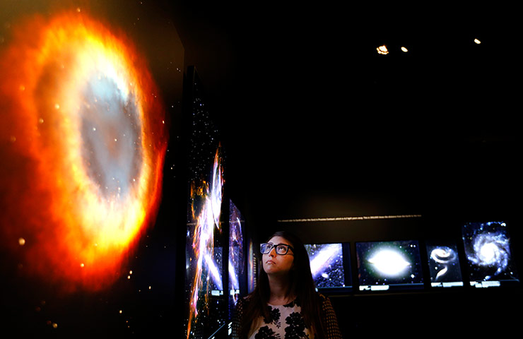 Visions of the universe: A museum employee looks at one of the one hundred plau images of space on d