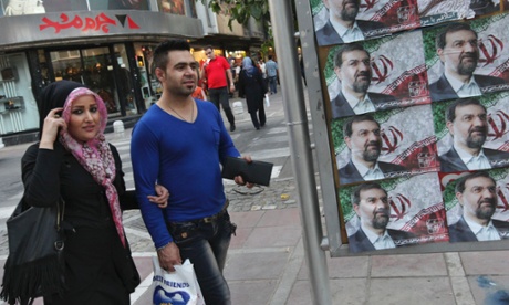 Iranians walk past posters of the presidential candidate Mohsen Rezaei, a former Revolutionary Guard commander.