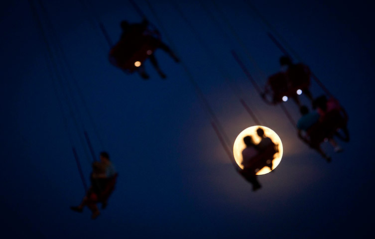 super moon: People ride the Luna Park Swing Ride as the Super Moon 