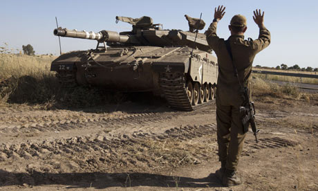 An Israeli soldier directs a Merkava tank in the Golan Heights near the Quneitra crossing with Syria