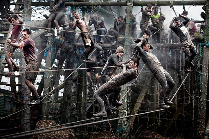 Tough Guy - Weekend: Men climb along ropes in muddy conditions