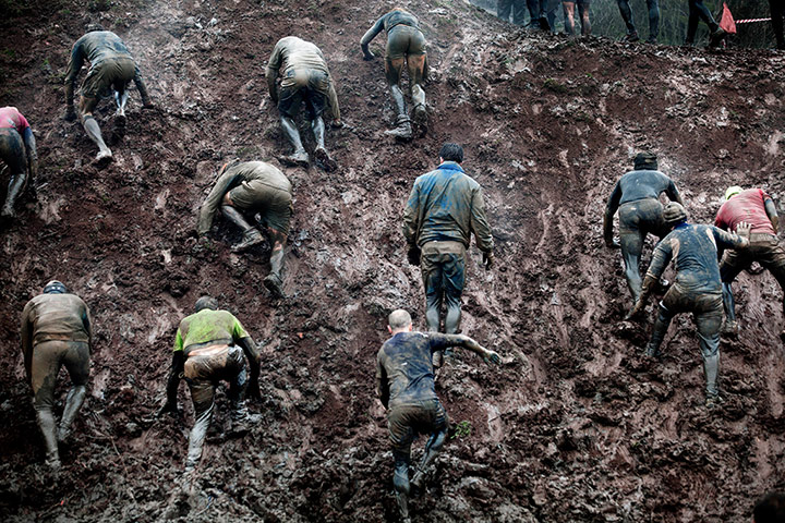 Tough Guy - Weekend: Men climb up a muddy hill at the annual Tough Guy competition