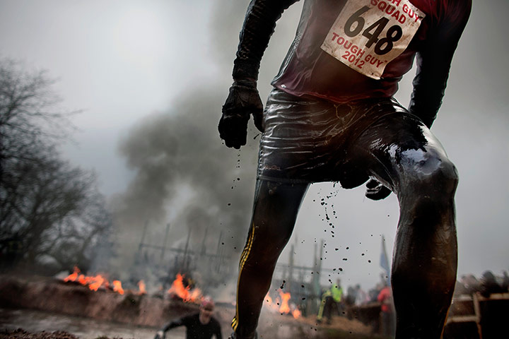 Tough Guy - Weekend: A mud covered in mud climbs out of a lake 