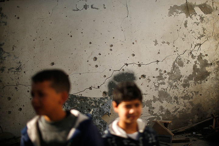 20 Photos: Boys in front of a damaged wall hit during an Israeli air strike in Gaza